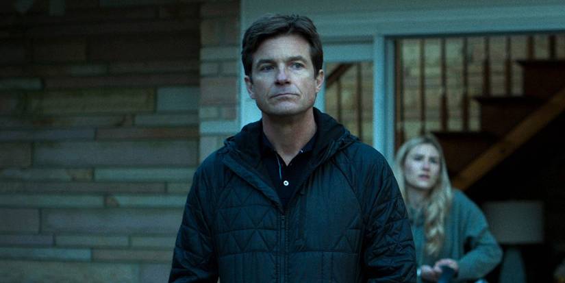 Jason Bateman in Ozark standing by his door, his daughter in the background.