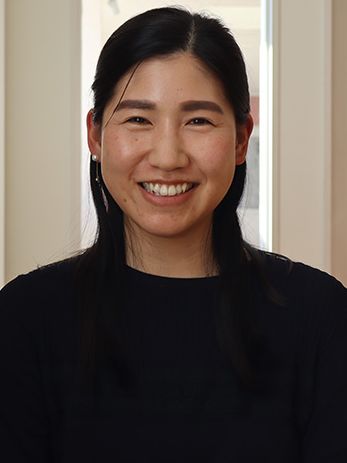 a smiling woman with her long black hair pulled back in a half-up, half-down style