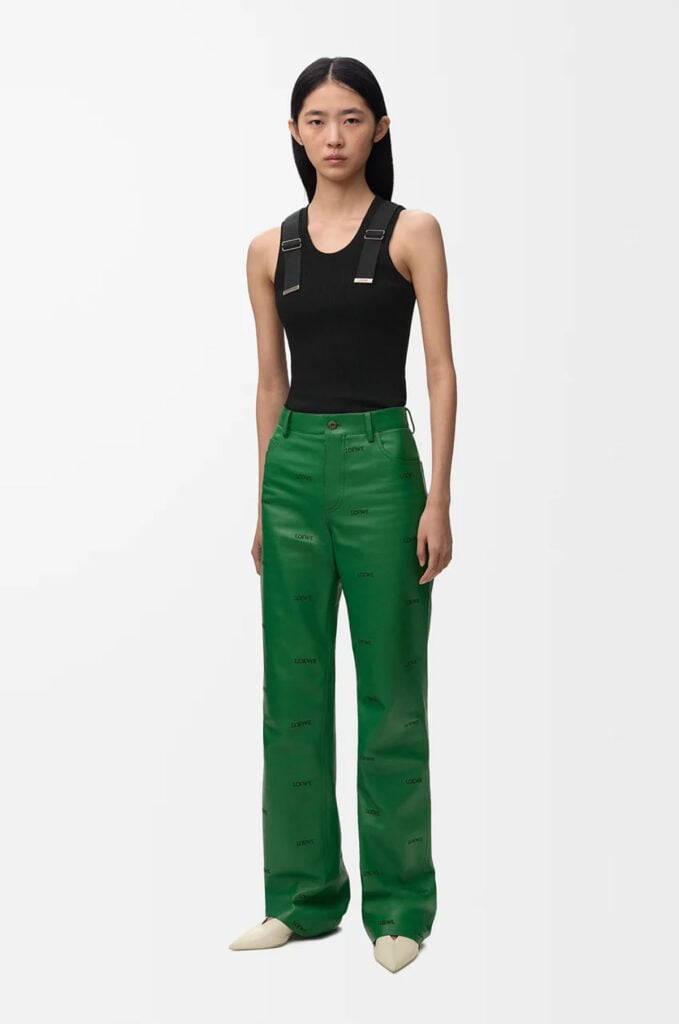 Loewe Pre-Fall 2026 runway look with green logo leather trousers and white vest.