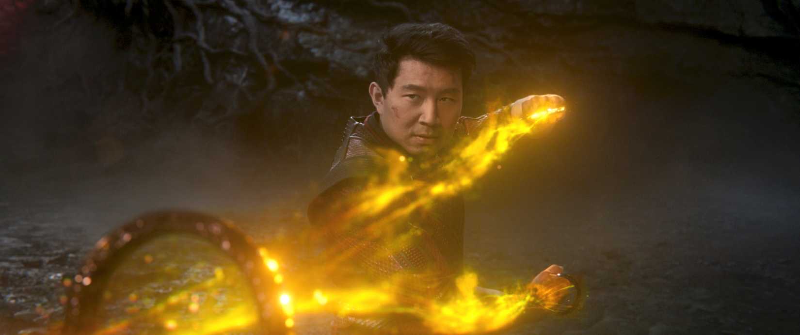 Simu Liu wields the Ten Rings, surrounded by yellow fire, as Shang-Chi in Shang-Chi and the Legend of the Ten Rings.