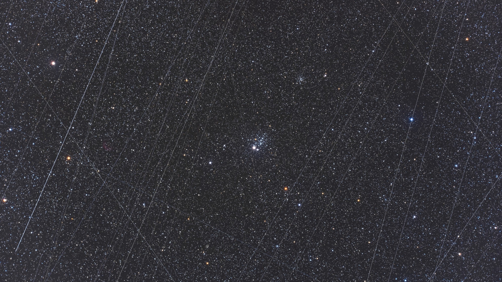 a photograph of the night sky, showing streaks of light crisscrossing in front of stars
