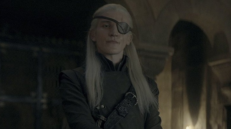 Ewan Mitchell as Aemond standing and frowning in House of the Dragon