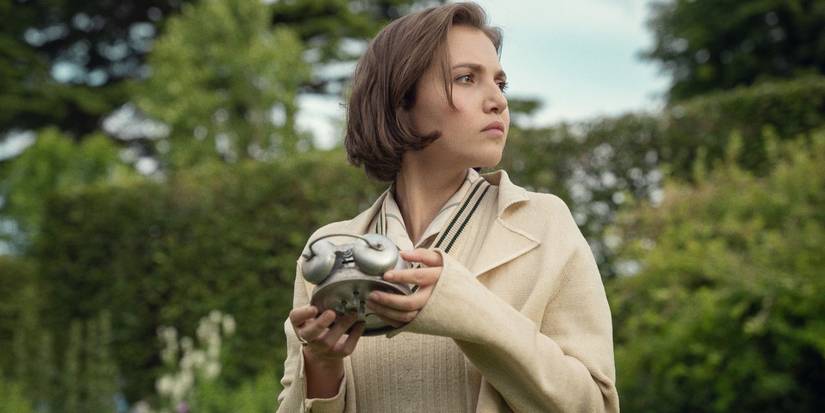 Mia McKenna-Bruce as Bundle with a camera looking to the distance in Agatha Christie's Seven Dials.