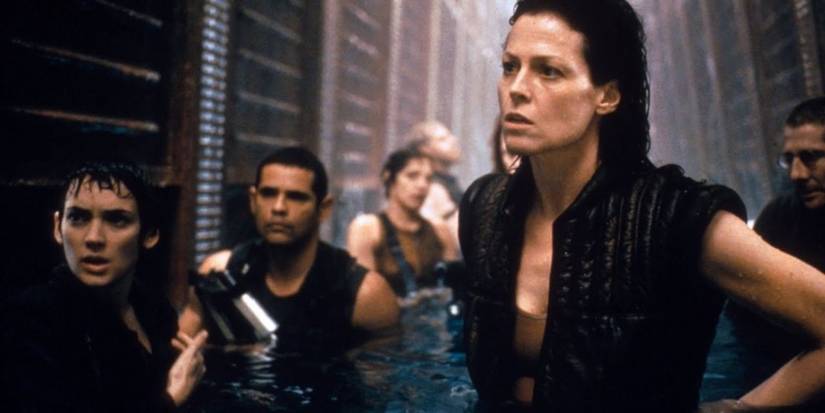 Ripley stands next to mercenaries submerged in water in Alien Resurrection.