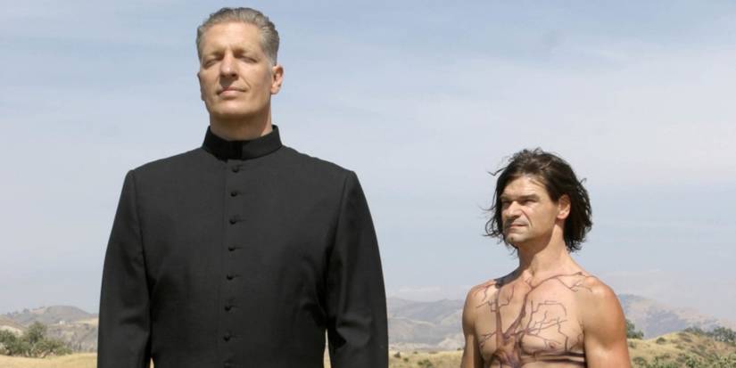 Justin stands next to a tattooed man in Carnivale.