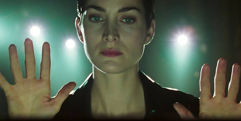 Carrie Anne Moss as Trinity facing the camera and raising her hands in The Matrix