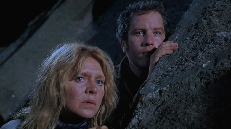 Richard Dreyfuss as Roy Neary and Melinda Dillon as Jillian Guiler in Close Encounters of the Third Kind, hiding and peering from behind a rock.