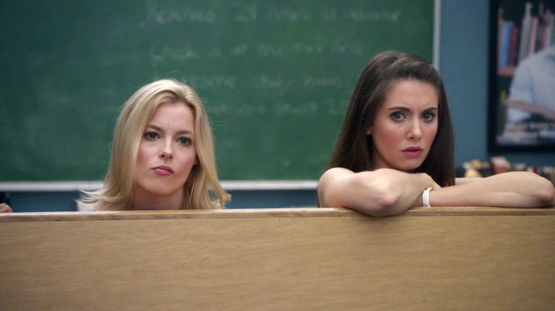 Britta (Gillian Jacobs) and Annie (Allison Brie) hide behind a table in Community