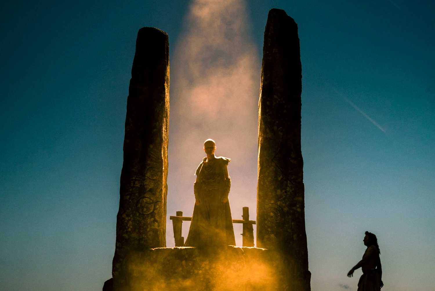 Fire and smoke-filled Druid ceremony between stone pillars.