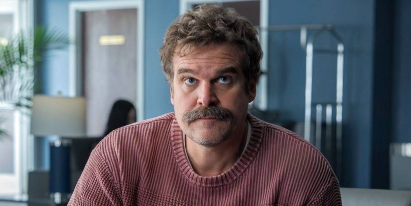 David Harbour as Floyd Smernitch looking up while in a pink sweater in DTF St. Louis