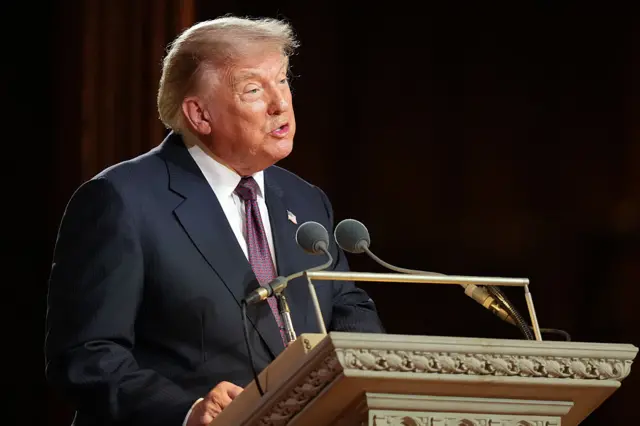 Trump at a lectern speaking into two microphones