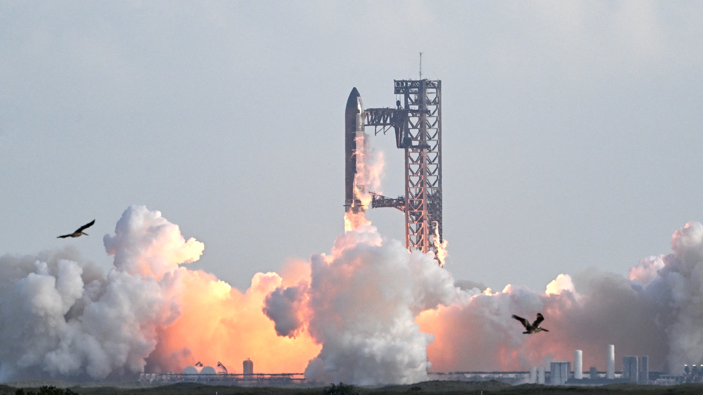A photo of SpaceX's Starship rocket launching from the ground with plume of fire and smoke
