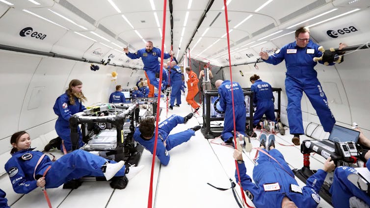 People in blue floating inside aircraft