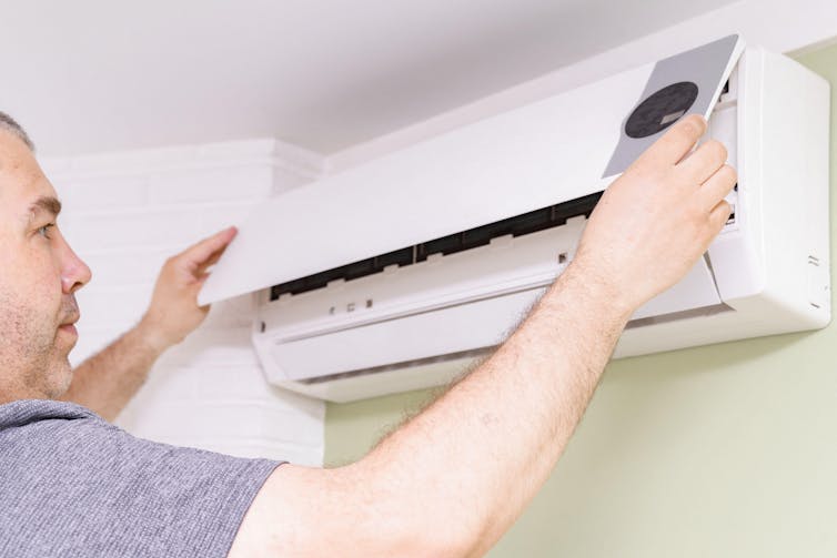 Man fiddles with indoor air con unit