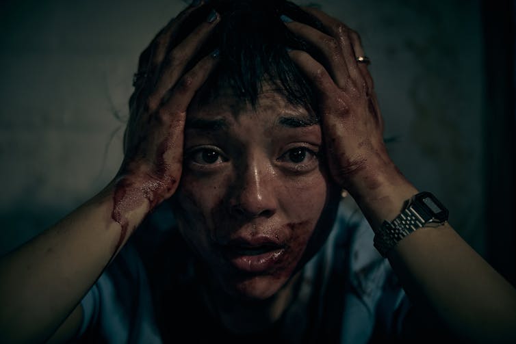Production image: Hana's face is covered in blood.