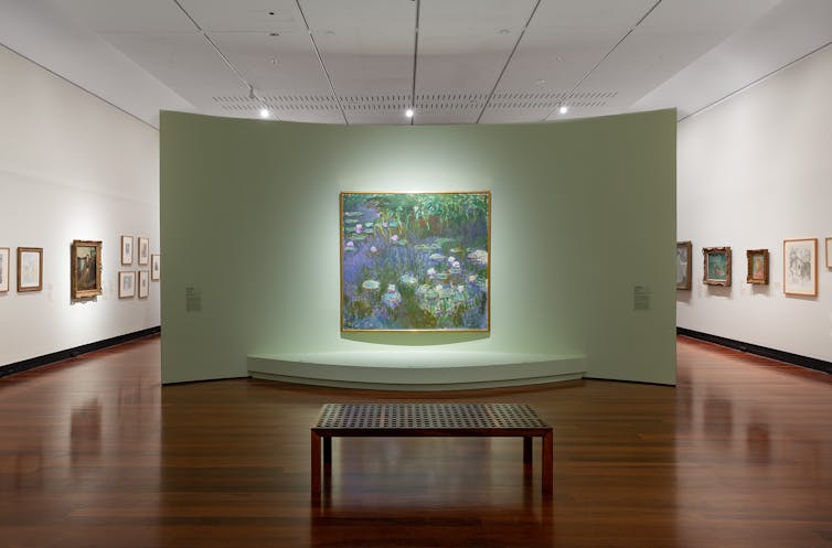 A painting of waterlilies hung on a curved green wall.