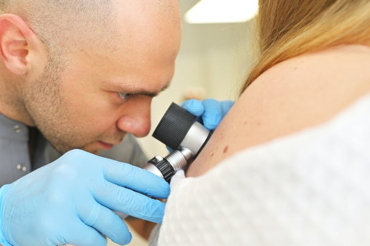 A dermatologist inspecting a patient's skin.
