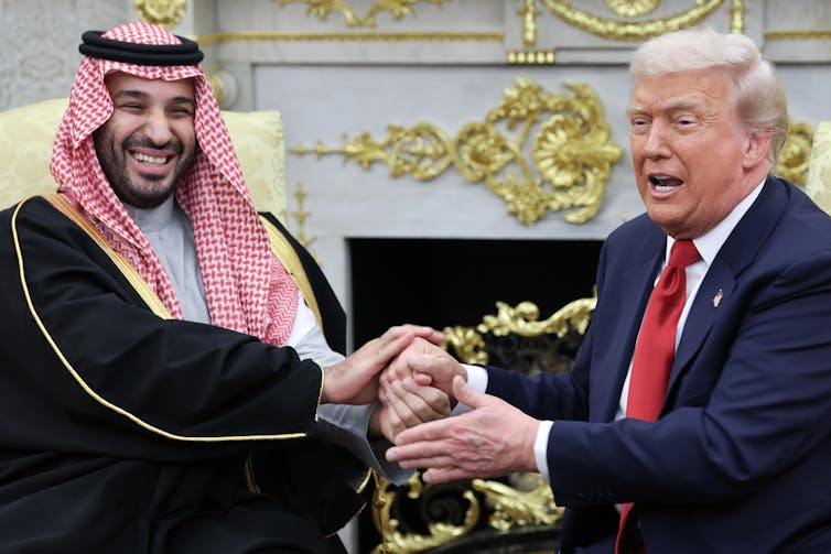 Two men shake hands.