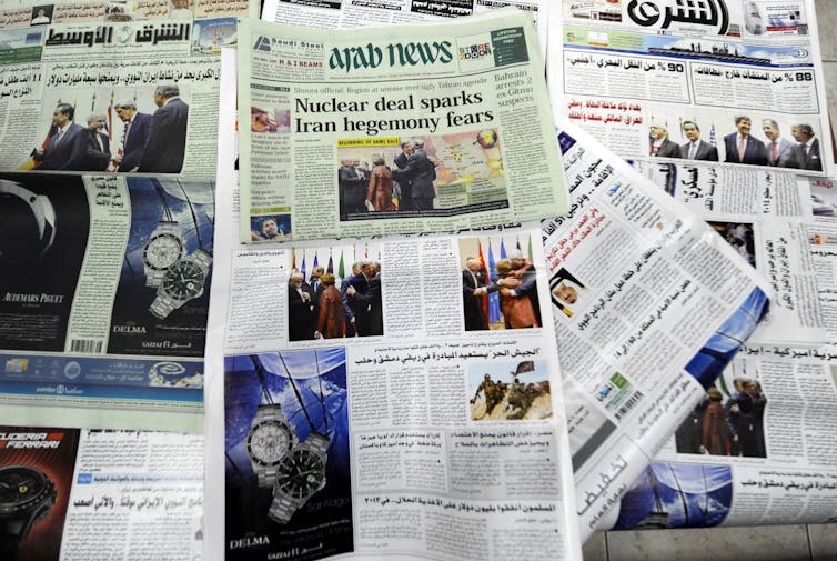 Newspapers show headlines regarding the 2013 Iran nuclear deal.