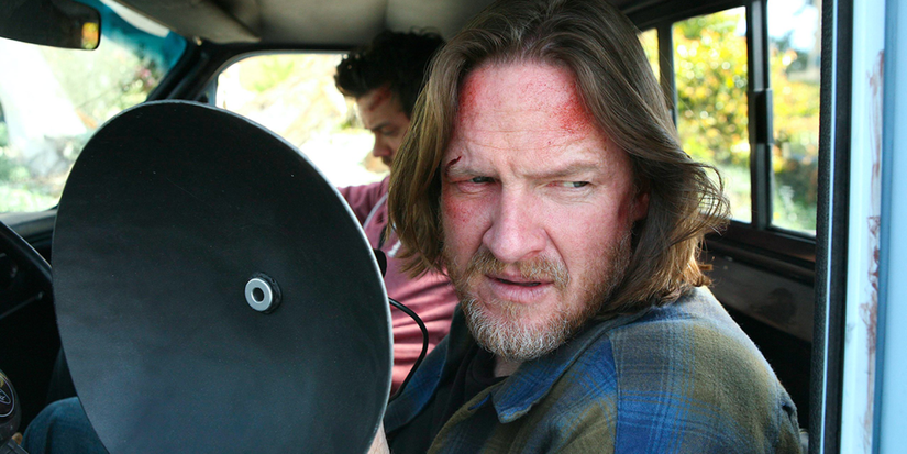 Two men sit in a vehicle and one holds up a small satellite dish in Terriers.