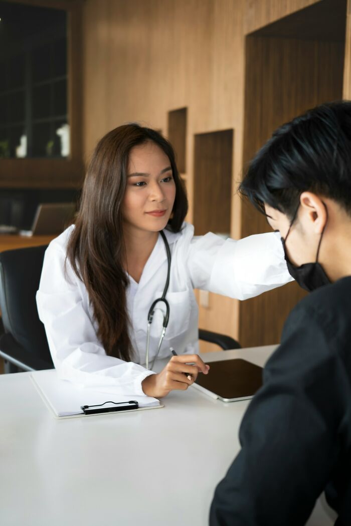 A female doctor with a stethoscope provides comfort to a patient in a mask, illustrating what doctors do when patients are faking.
