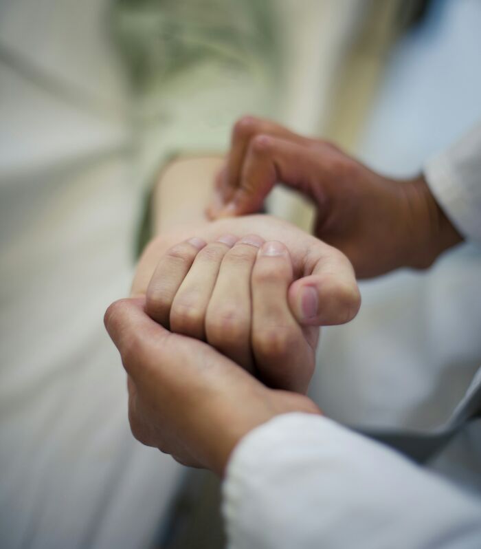 A doctor checking a patient's pulse, attentive to patient care and faking it scenarios.