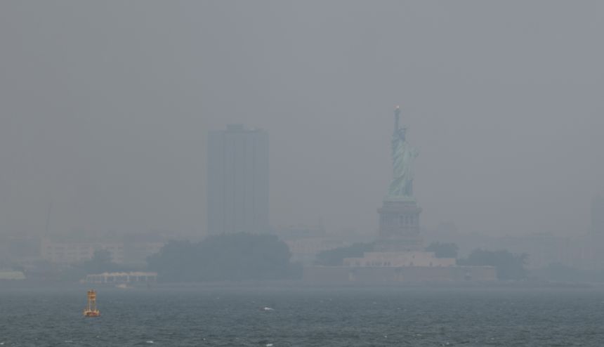 Haze from Canadian wildfires blankets the Statue of Liberty, as seen from a Brooklyn pier in New York on July 15, 2026.