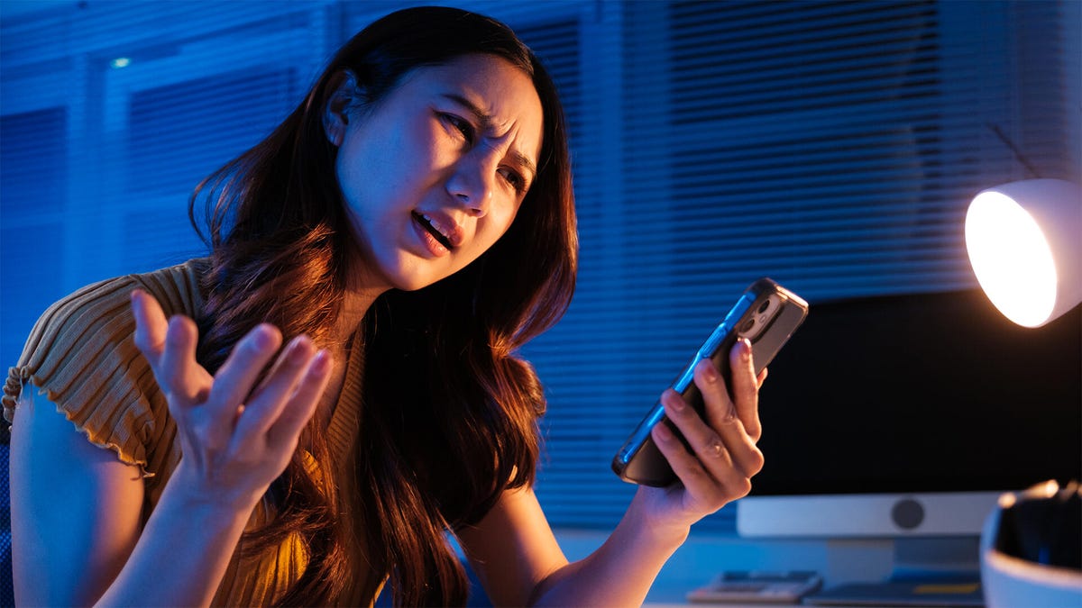 A woman looking angrily at her phone.