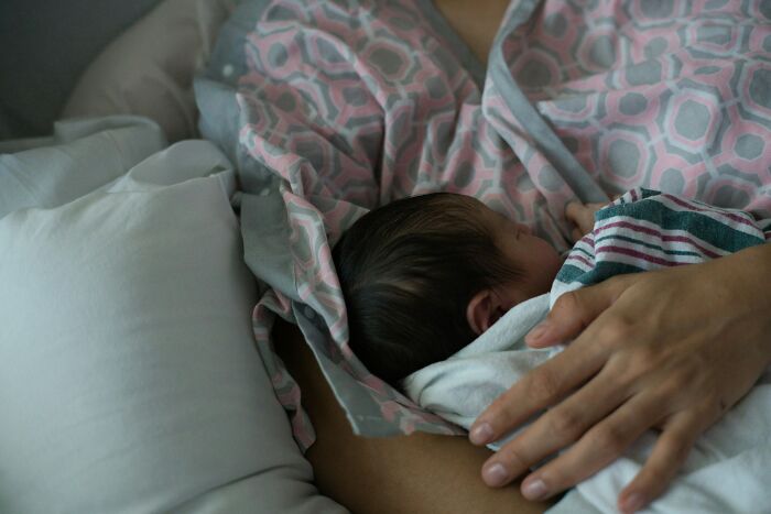 A mother cradling her newborn baby in a hospital bed, evoking powerful hospital stories.
