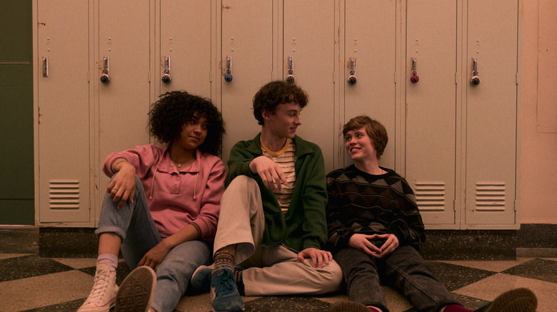 Dina, Stanley, and Sydney sitting with their backs against lockers in 