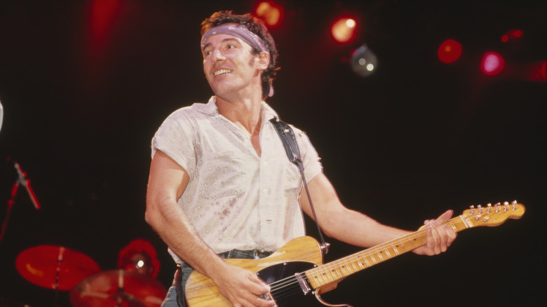 Bruce Springsteen holding guitar and smiling onstage