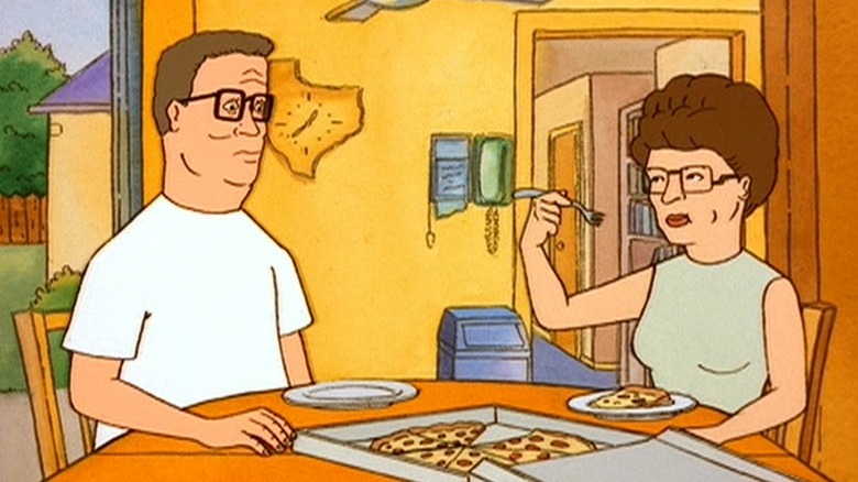Hank and Peggy sitting at the table and eating pizza on King of the Hill S1E7