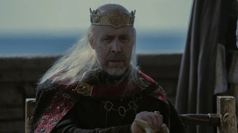 Paddy Considine as Viserys with thinning hair sitting outside in House of the Dragon