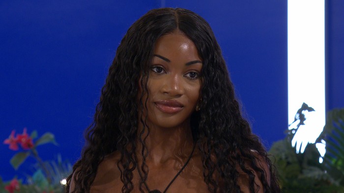Love Island S13 Victoria stood at the Love Island fire pit, looking ahead with calm expression.