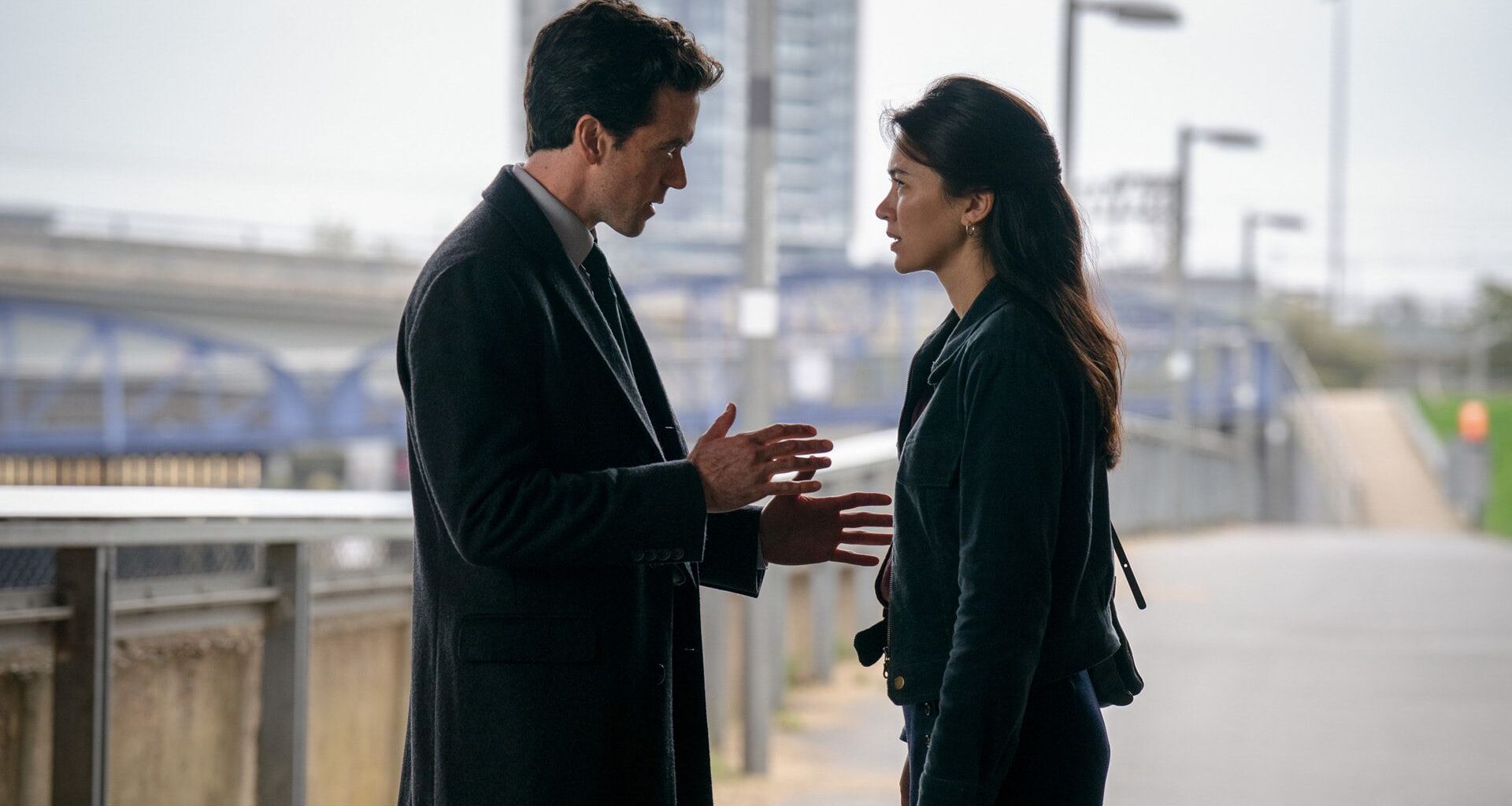 a man and woman talking on a bridge