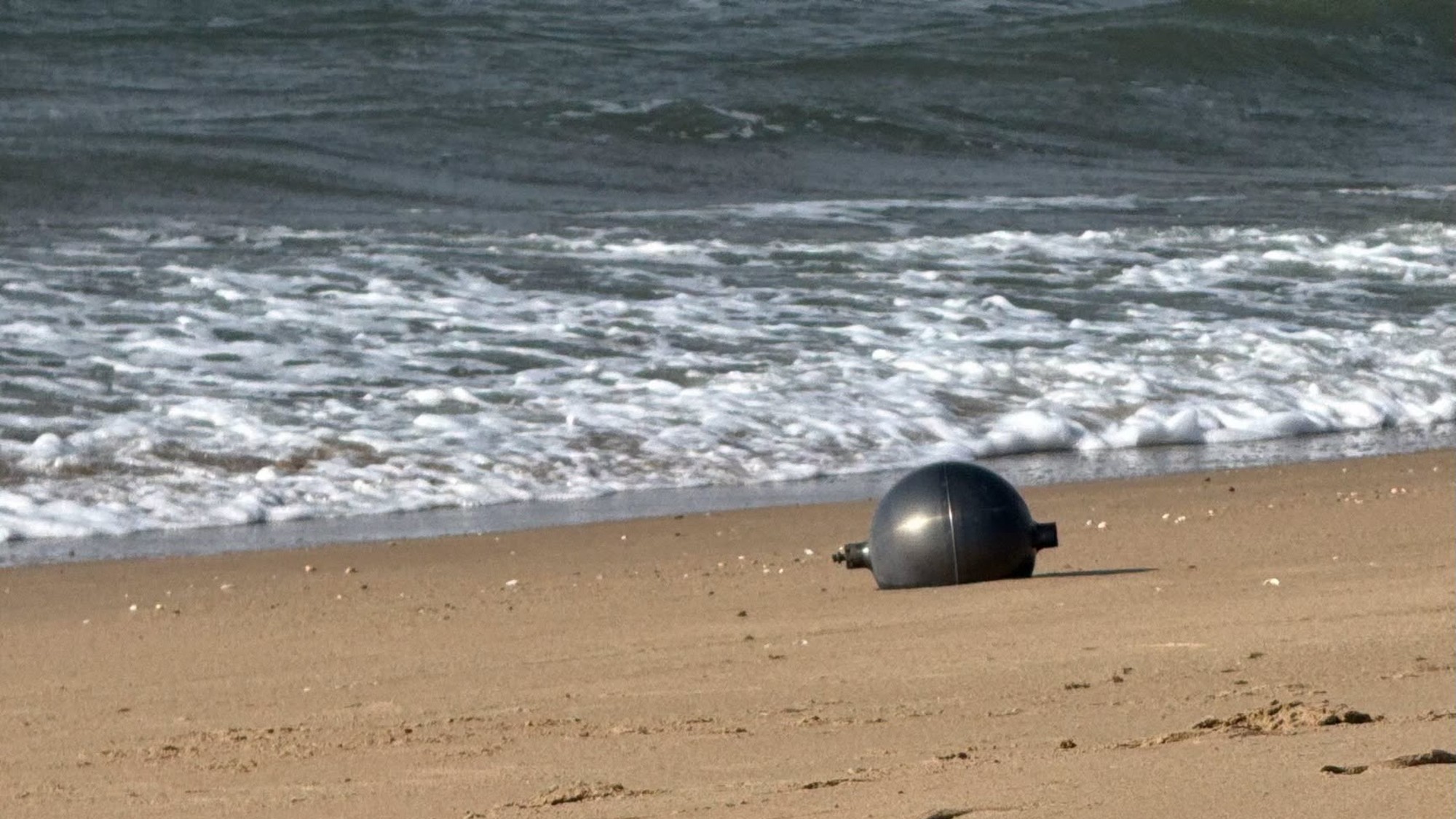 a metallic sphere on a sandy beach