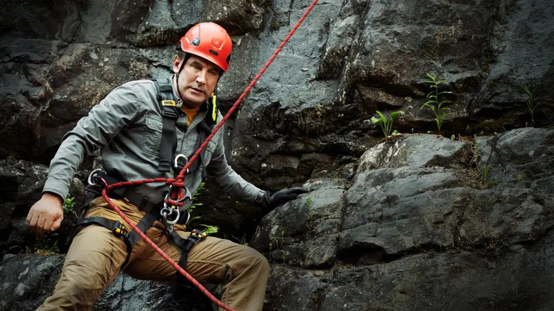 John West (William Baldwin) is lowered down a cliff face by a rope in Northern Rescue