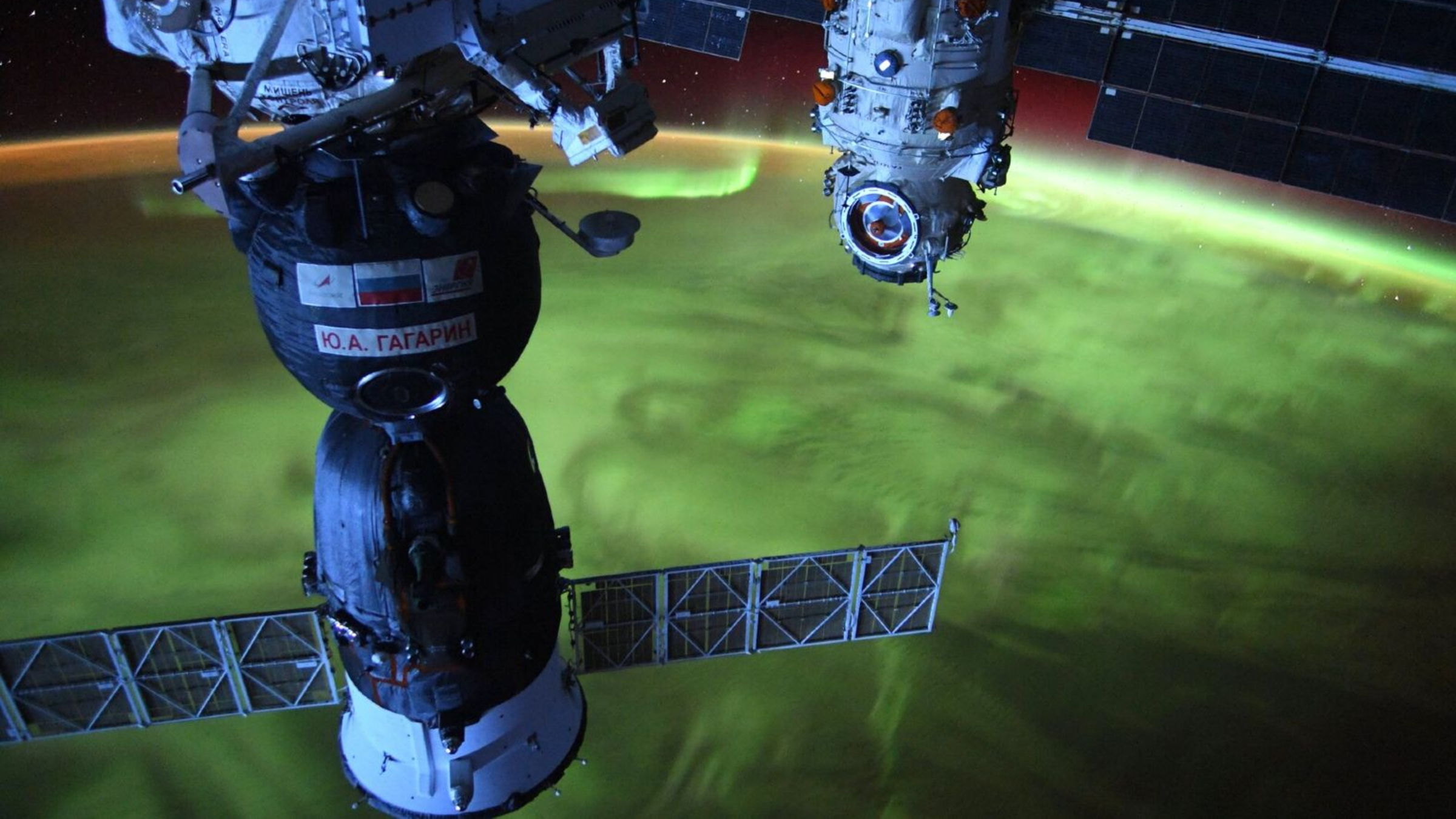 A photo of a Russian satellite orbiting Earth with auroras covering our planet