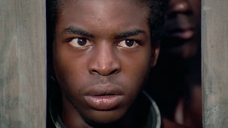 Kunta Kinte, looking on in horror in a wooden cage