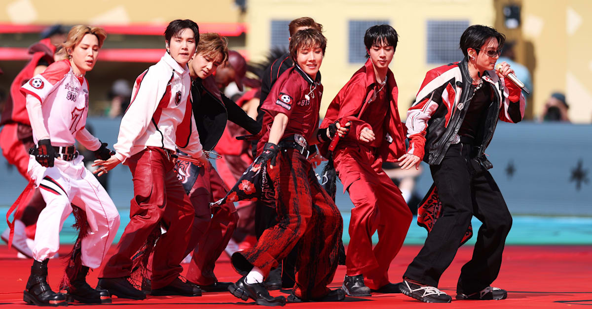 BTS in coordinated red and black outfits dancing energetically on a red stage.