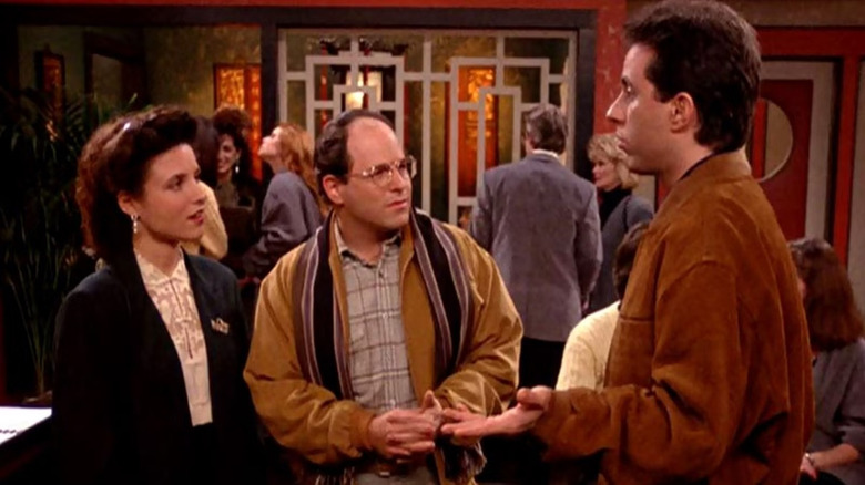Elaine (Julia Louis-Dreyfus), George (Jason Alexander), and Jerry (Jerry Seinfeld) wait for a table in Seinfeld