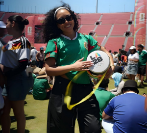Aaliyah holding a custom RallyMates inflatable fan drum in a stadium-inspired setting.