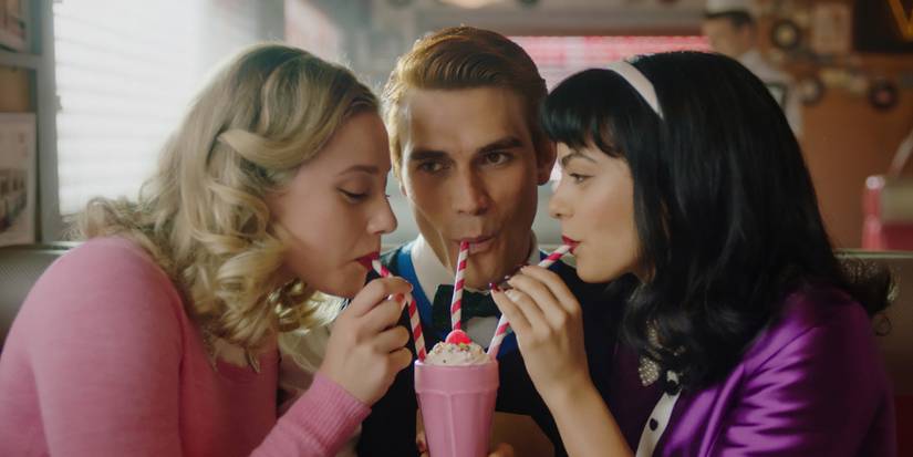 Archie shares a milkshake with Veronica and Betty in Riverdale.