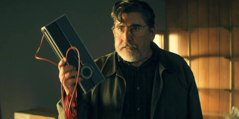 Alfred Molina holding up a piece of equipment and looking angry in The Boroughs