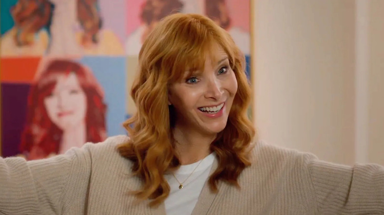 Lisa Kudrow as Valerie Cherish wearing a white shirt and beige sweater while smiling with her arms outstretched in a scene from 