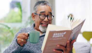 Person holding coffee mug and reading book.