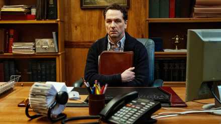 Matthew Rhys gripping a bag and staring dully ahead in Widow's Bay
