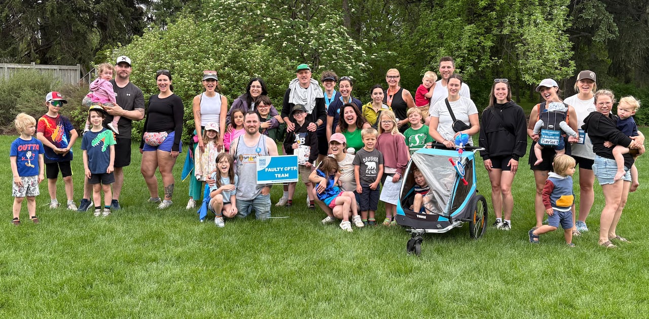 A large group of people pose together for a picture in a grassy park.