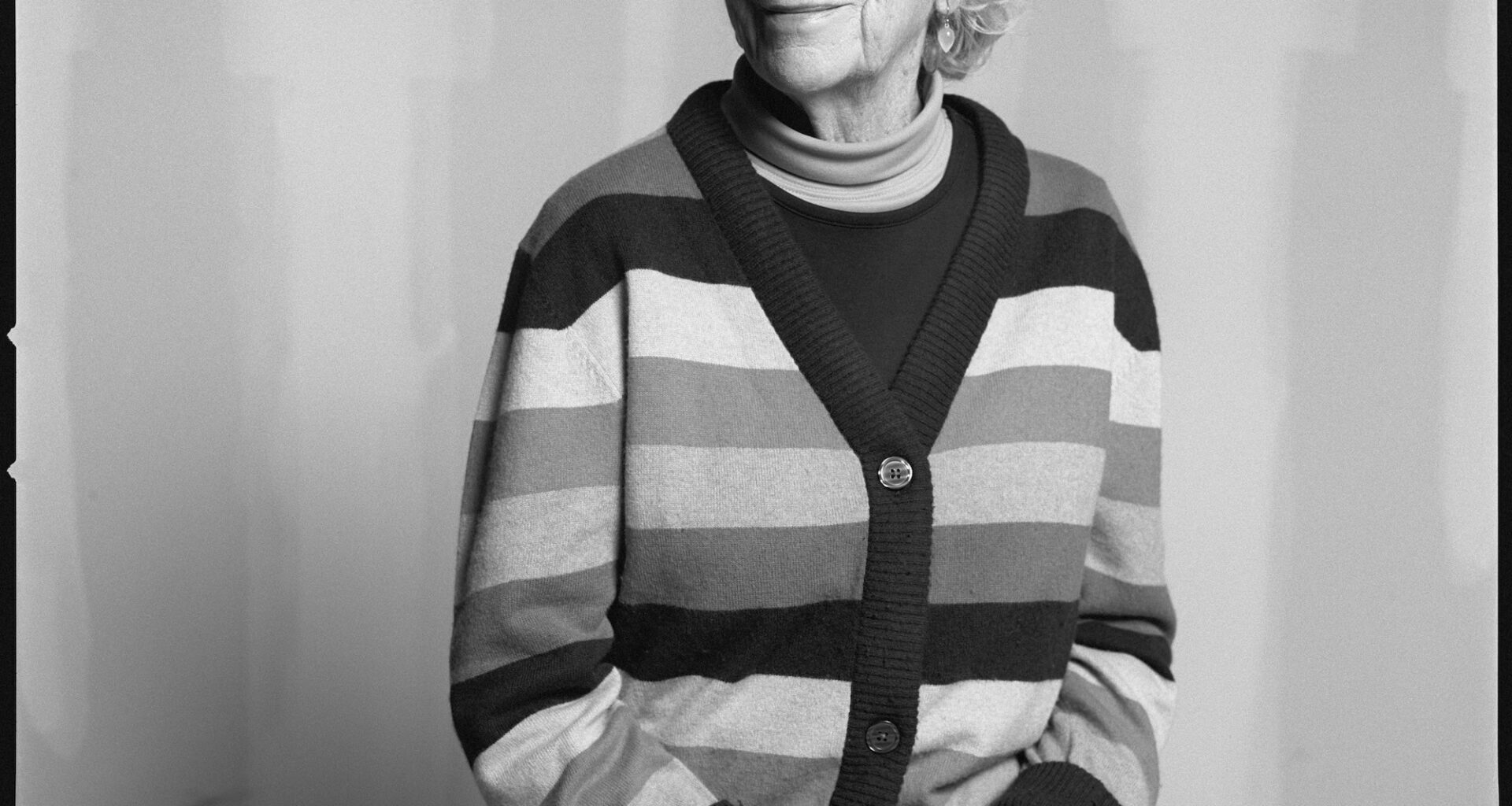 black and white photo of Mary Heilmann, sat in a striped cardigan