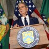 Treasury Secretary Scott Bessent stands behind a lectern equipped with a microphone as he speaks at a news conference at the Treasury Department on Monday. The department's seal is on the front of the lectern, and three flags are behind Bessent: a U.S. flag flanked on each side by a Treasury Department flag.